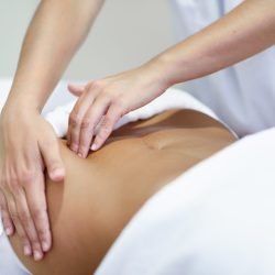 Female patient is receiving treatment by professional osteopathy therapist. Woman receiving a belly massage at spa salon